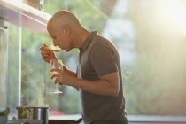 Man drinking white wine and cooking at stove in kitchen — Stock Photo