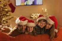 Ritratto famiglia sorridente indossa cappelli di Babbo Natale sul divano del soggiorno — Foto stock