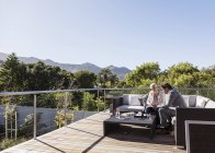Businessman and businesswoman working on sunny luxury balcony patio sofa — Stock Photo