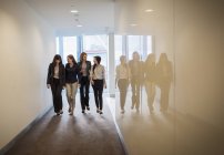 Деловые женщины, идущие в ряд по офисному коридору — стоковое фото