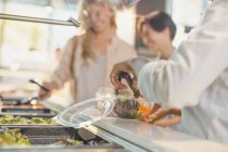 Jovens mulheres servindo salada no bar de saladas no mercado de mercearias — Fotografia de Stock