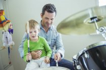 Padre e figlio suonano la batteria insieme — Foto stock