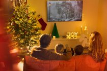 Родина дивиться телевізор в різдвяні вітальні — стокове фото