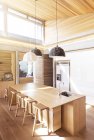 Luces colgantes modernas colgando sobre isla de cocina de madera - foto de stock