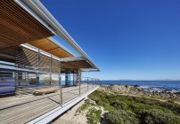 Современная витрина роскошного дома с видом на океан под солнечным голубым небом — стоковое фото
