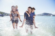 Family running in water on beach — Stock Photo