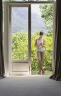 Жінка стоїть на терасі в розкішному сучасному будинку — стокове фото