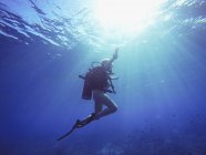 Mergulhador subaquático sob feixes de sol — Fotografia de Stock