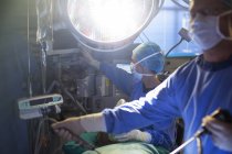 Chirurgiens masculins et féminins effectuant une chirurgie laparoscopique en salle d'opération — Photo de stock