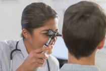 Female doctor using otoscope in ear of patient — Stock Photo