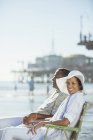 Portrait of couple relaxing in lawn chairs on sunny beach — Stock Photo
