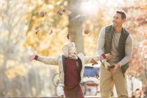 Father and son throwing autumn leaves overhead — Stock Photo