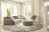 Tapete redondo sob sofá e otomano na sala de estar — Fotografia de Stock