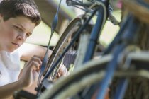 Niño examinando bicicleta al aire libre - foto de stock
