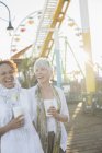 Senior women laughing and drinking coffee at amusement park — Stock Photo