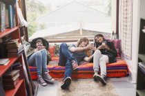 Young friends hanging out using cell phones in apartment window — Stock Photo