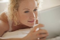 Крупним планом жінка використовує цифровий планшет у ліжку — стокове фото