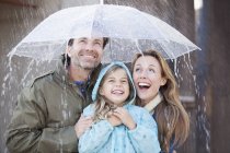 Famiglia entusiasta sotto l'ombrello in acquazzone — Foto stock