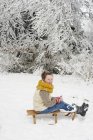 Caucasian happy girl sitting on wooden sled in snow — Stock Photo