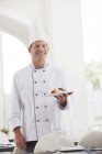 Шеф-кухар тримає тарілку їжі в ресторані — стокове фото