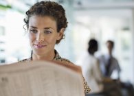 Geschäftsfrau liest Zeitung am Schreibtisch — Stockfoto