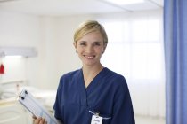 Enfermera sonriendo en la moderna habitación del hospital - foto de stock