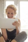 Donna sorridente utilizzando tablet digitale — Foto stock