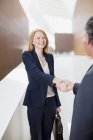 Усміхнена бізнес-леді тремтить руками з бізнесменом — стокове фото