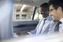 Бизнесмены, использующие ноутбук в автомобиле — стоковое фото