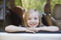 Smiling girl leaning out car window — Stock Photo