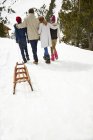 Задний вид на семью, идущую по снегу вместе — стоковое фото