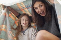 Enthusiastic mother and daughter under blanket — Stock Photo