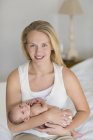 Mutter wiegt Neugeborenes auf Bett — Stockfoto