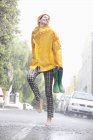 Счастливая женщина танцует босиком на дождливой улице — стоковое фото