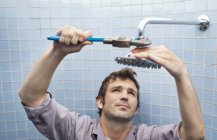 Plumber working on shower head in bathroom — Stock Photo