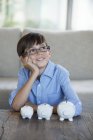 Boy sitting with piggy banks at coffee table — Stock Photo