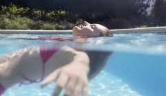 Vista lateral de la mujer flotando en la piscina - foto de stock