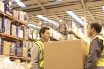 Workers carrying box in warehouse — Stock Photo