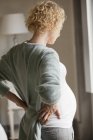 Pregnant woman holding back in pain — Stock Photo