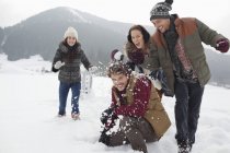 Amici giocosi che si godono la lotta con la palla di neve sul campo — Foto stock