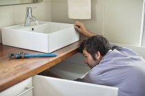 Male plumber working under kitchen sink — Stock Photo