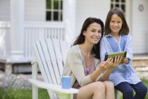 Mother and daughter using digital tablet outdoors — Stock Photo