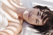 Ritratto di donna sorridente sdraiata a letto — Foto stock