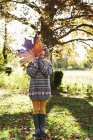 Menina brincando com folha de outono ao ar livre — Fotografia de Stock