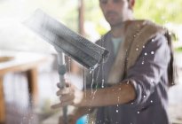 Skillful caucasian man washing window with squeegee — Stock Photo