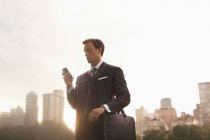 Бизнесмен, использующий мобильный телефон в городском парке — стоковое фото
