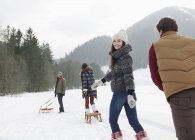 Друзья тянут санки на снежном поле — стоковое фото