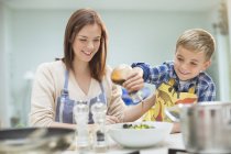 Madre e figlio fare insalata in cucina — Foto stock