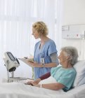 Nurse checking equipment in aging patient's hospital room — Stock Photo