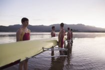 Rowing team holding scull in lake at dawn — Stock Photo